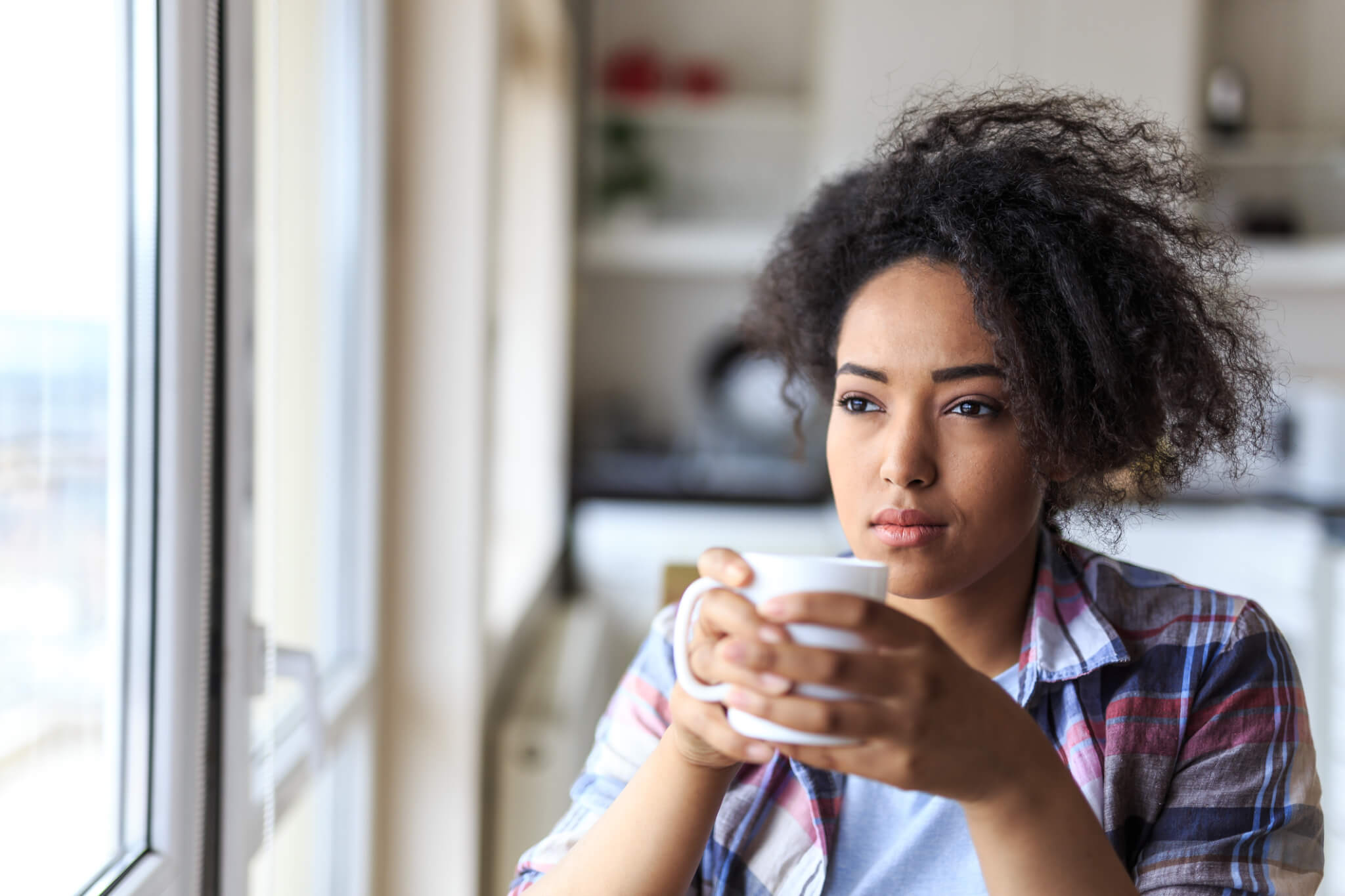 African woman drinking cup of coffee at home