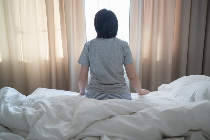 Back view of woman feeling depression and sitting on the bed